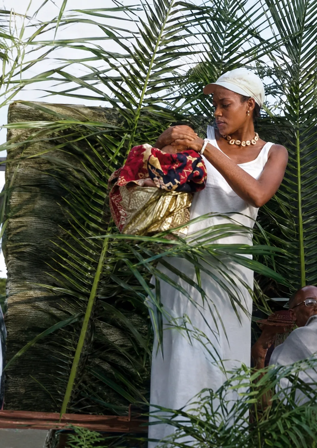 Une femme reçoit une bénédiction lors d'une cérémonie, étoffes de raphia rouge — la transmission au sein de la communauté